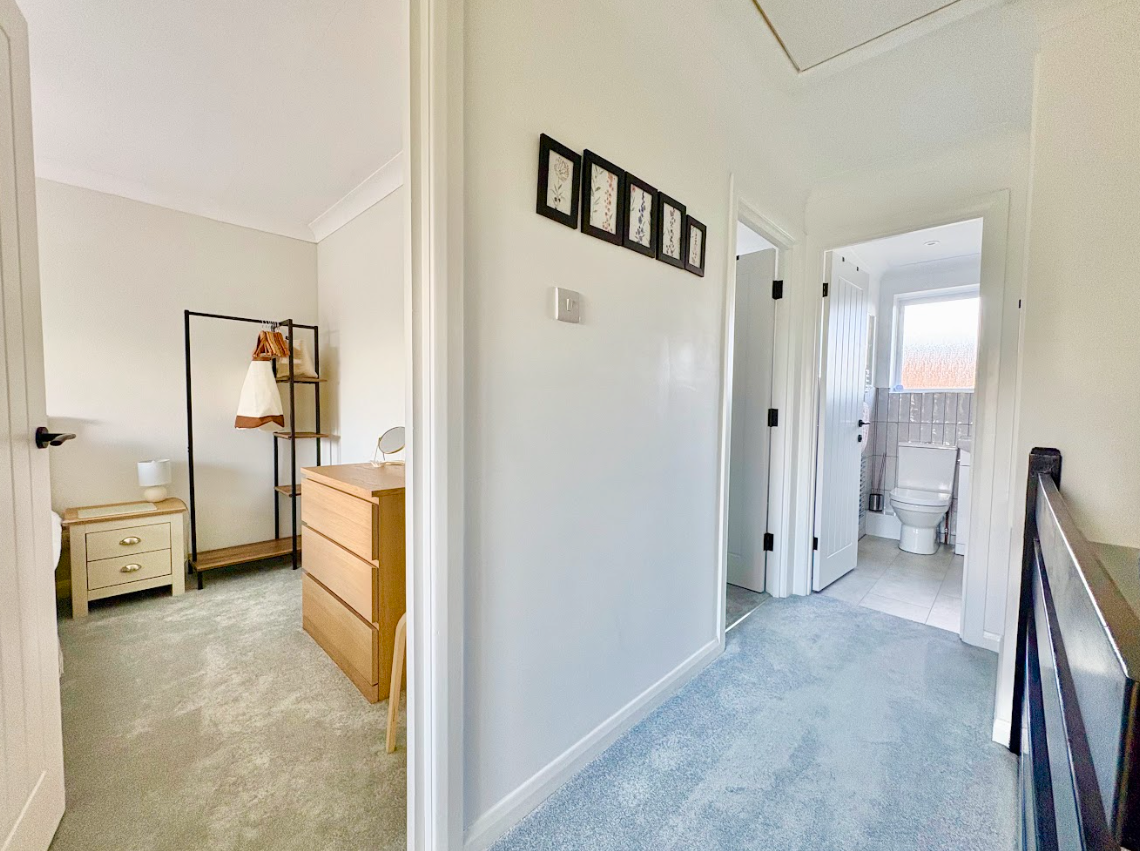 A hallway leading to a bedroom and a bathroom in a house.