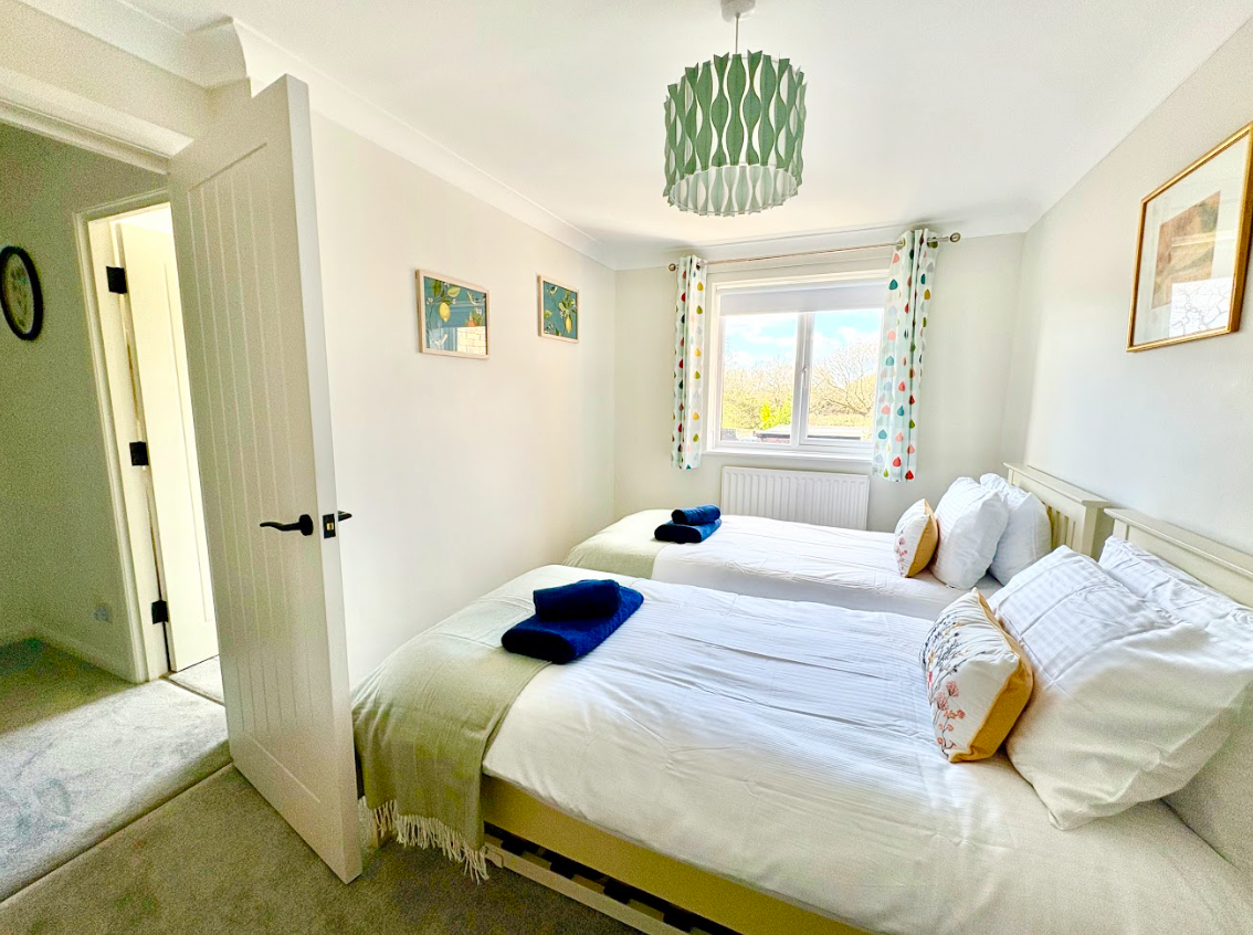 A bedroom with two twin beds and a window.