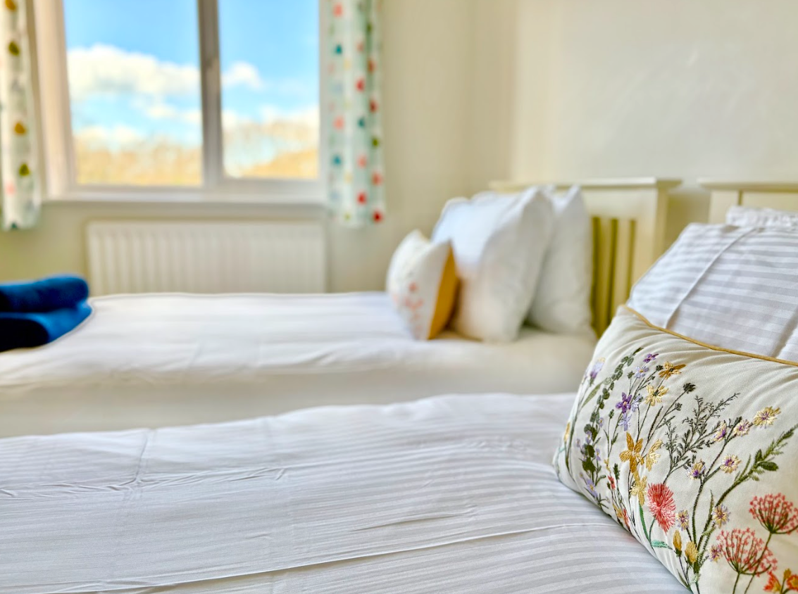A bedroom with two beds and a window.
