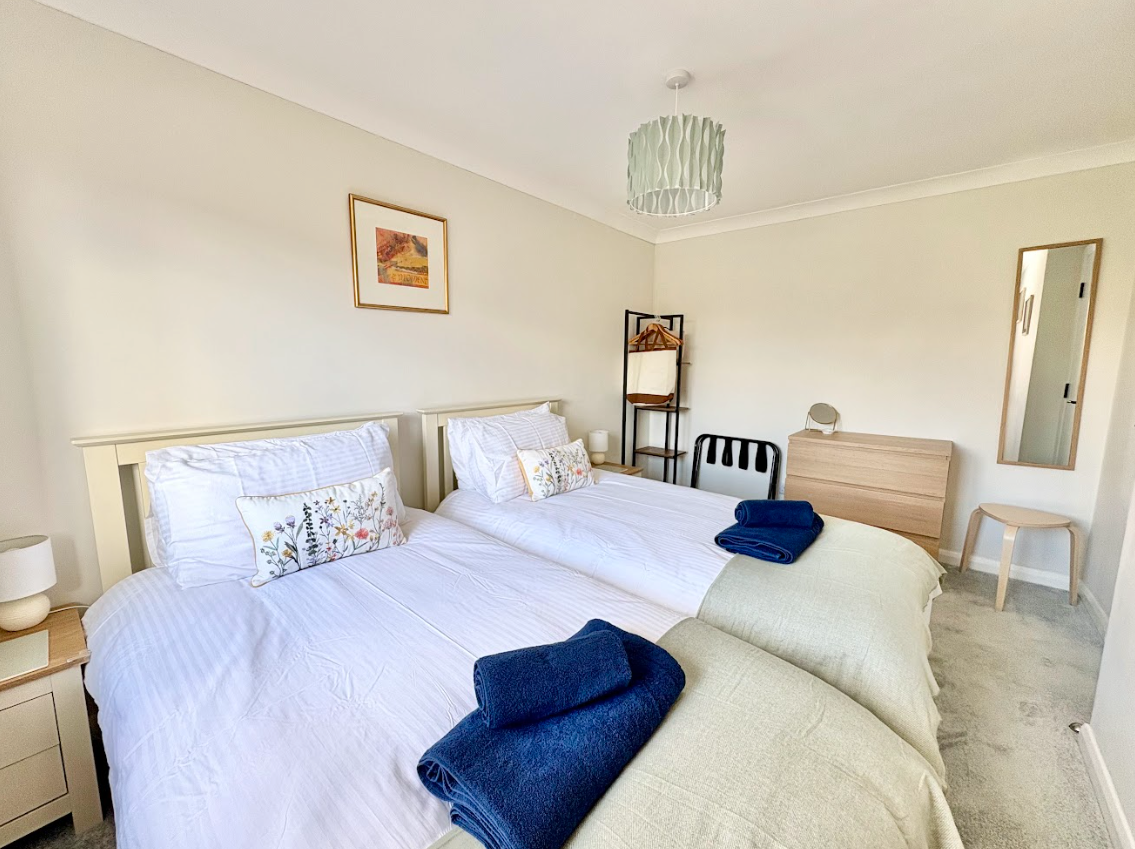 A bedroom with two beds , a dresser and a mirror.