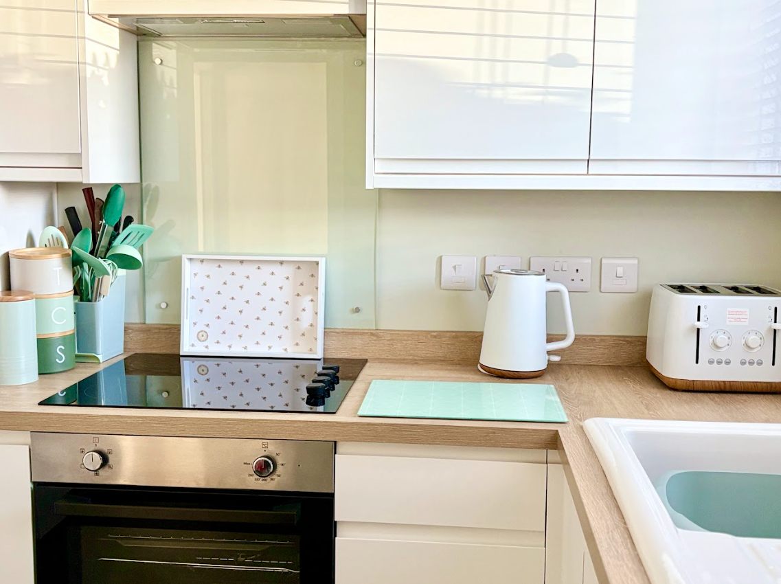 A kitchen with white cabinets , a stove top oven , a toaster oven , and a sink.