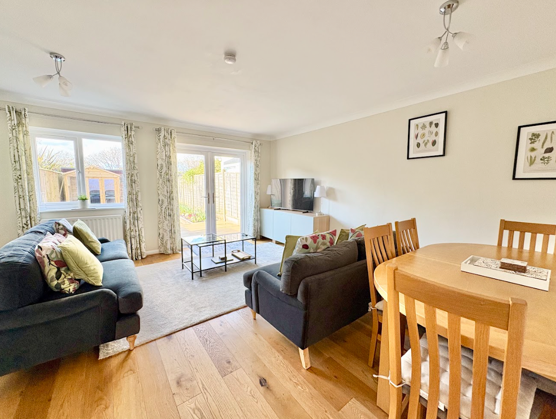 A living room with a couch , chairs , a table and a television.
