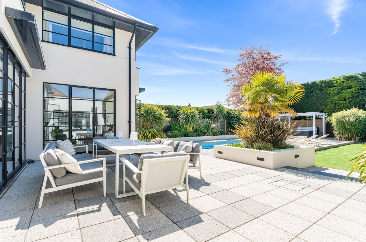 There is a patio with a table and chairs in front of a house.