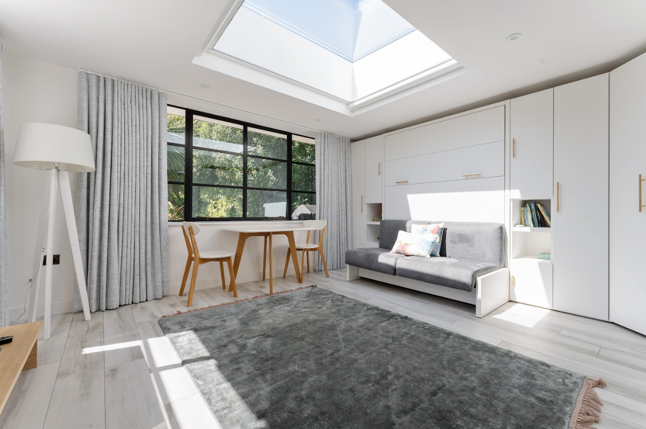A living room with a couch , table , chairs and a skylight.