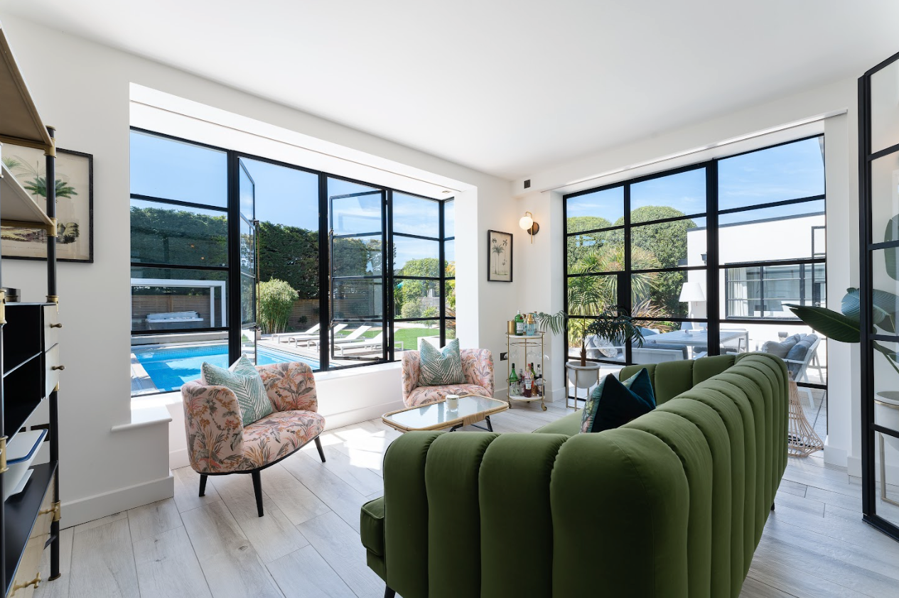 A living room with a green couch , two chairs , and a large window.
