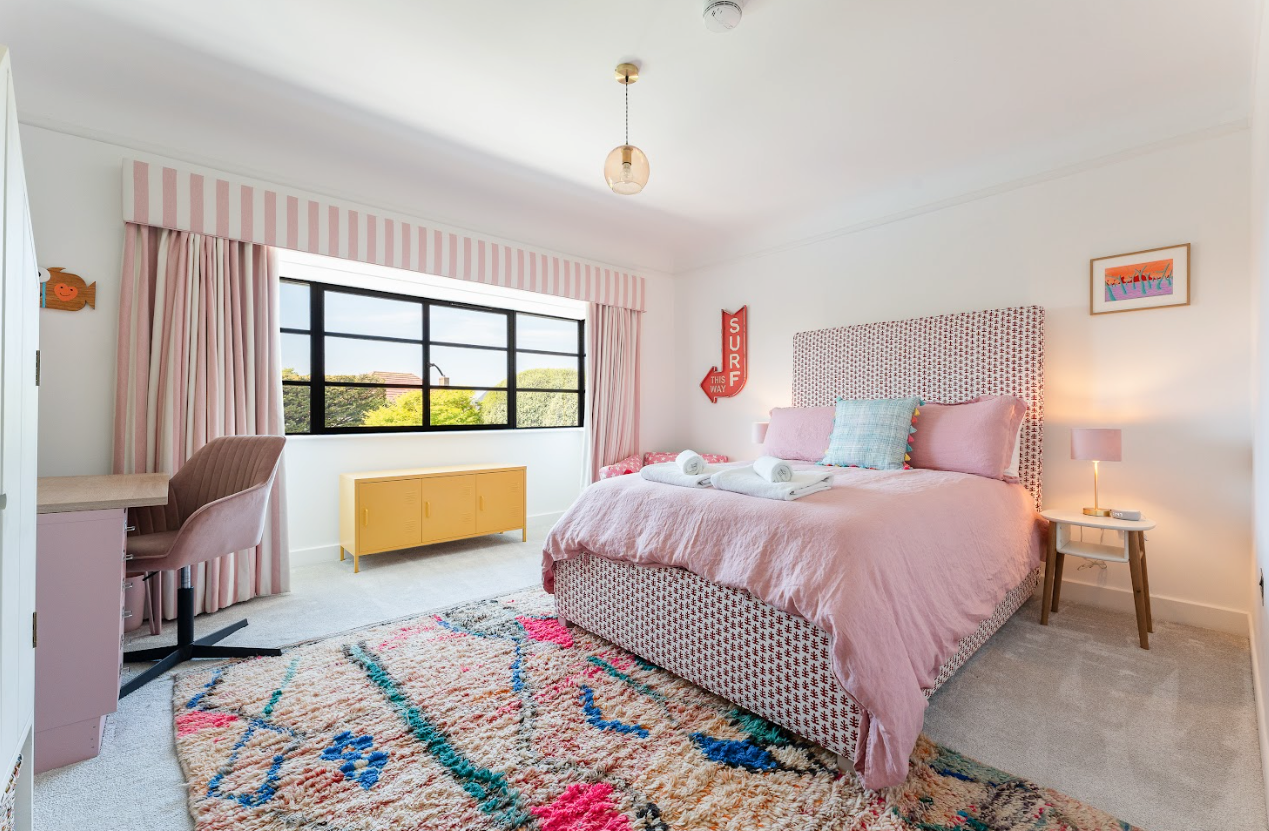 A bedroom with a bed , desk , chair and rug.