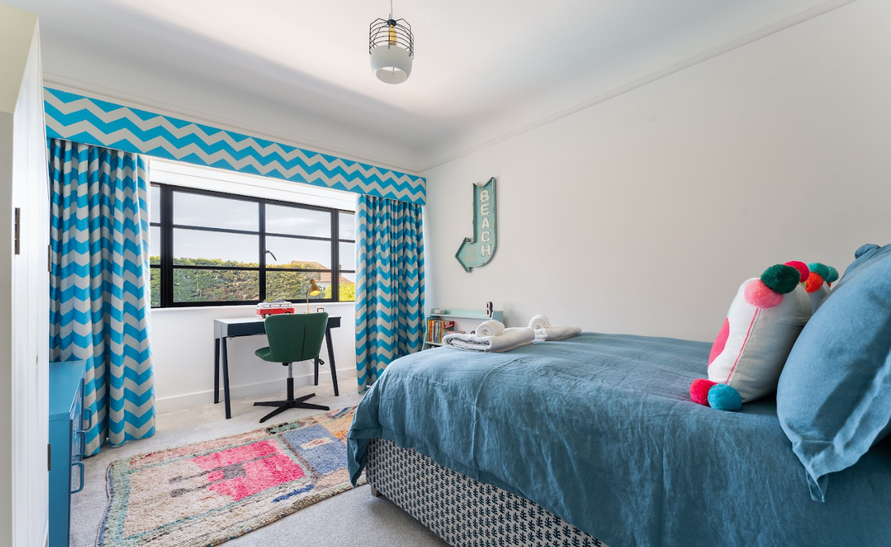 A bedroom with a bed , desk and window.