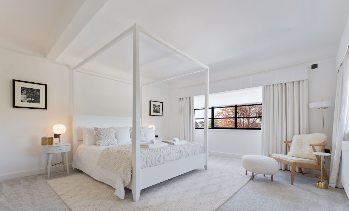 A bedroom with a canopy bed and a chair.