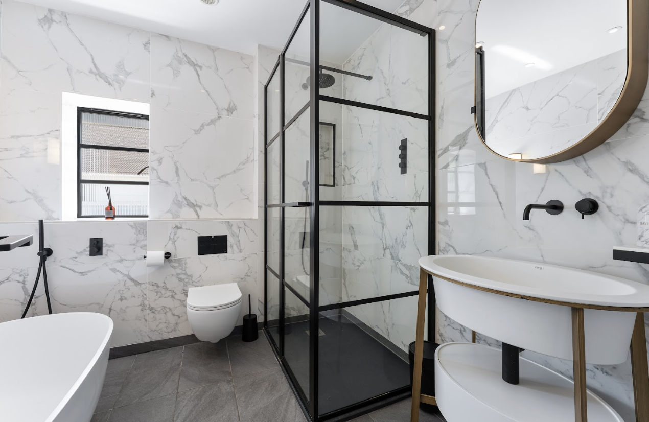 A bathroom with a walk in shower , sink , toilet and mirror.