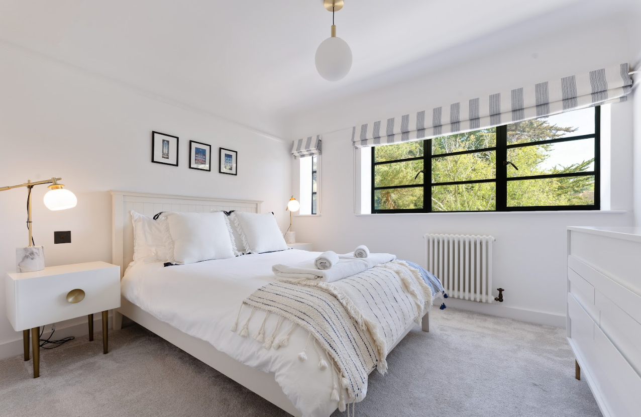 A bedroom with a bed , nightstand , dresser and window.