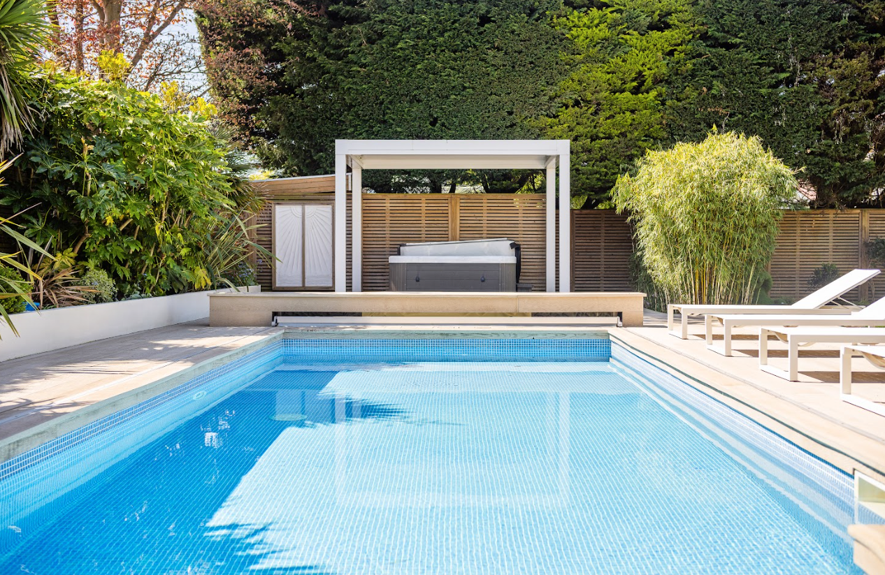 A large swimming pool with a hot tub in the backyard.