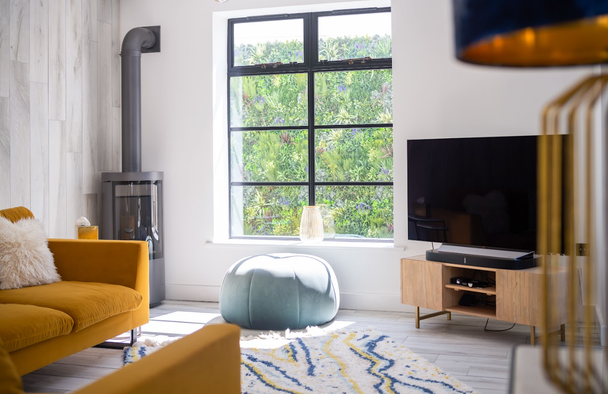 A living room with a yellow couch and a flat screen tv.
