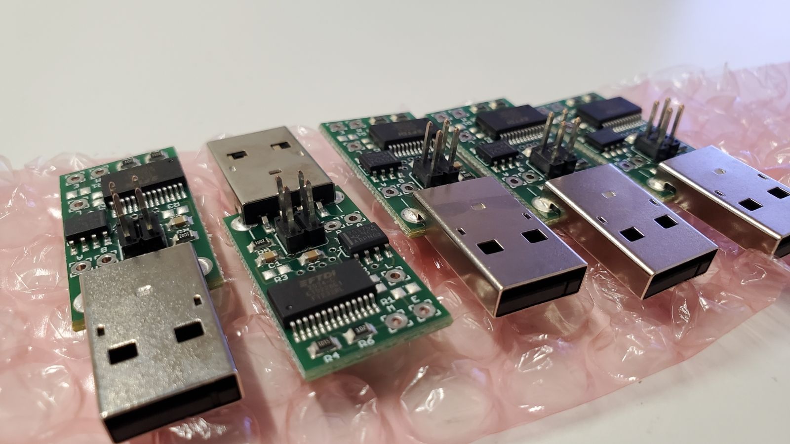 Four usb connectors are sitting on top of each other on a pink bubble wrap.