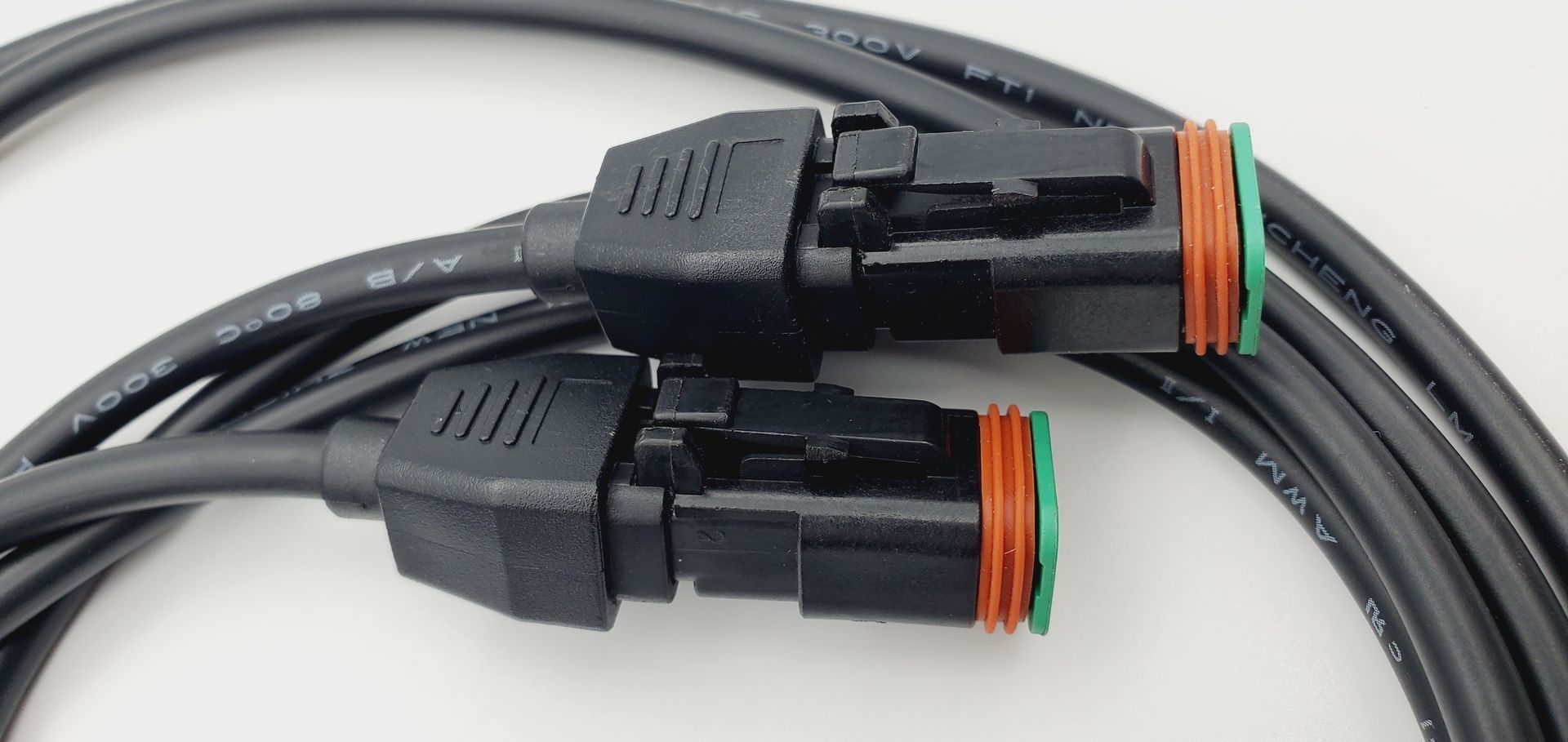 A close up of two black cables with connectors on a white surface.