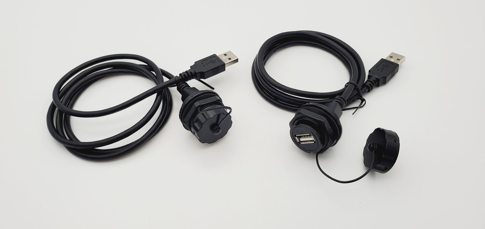 Two black usb cables are sitting on a white surface.