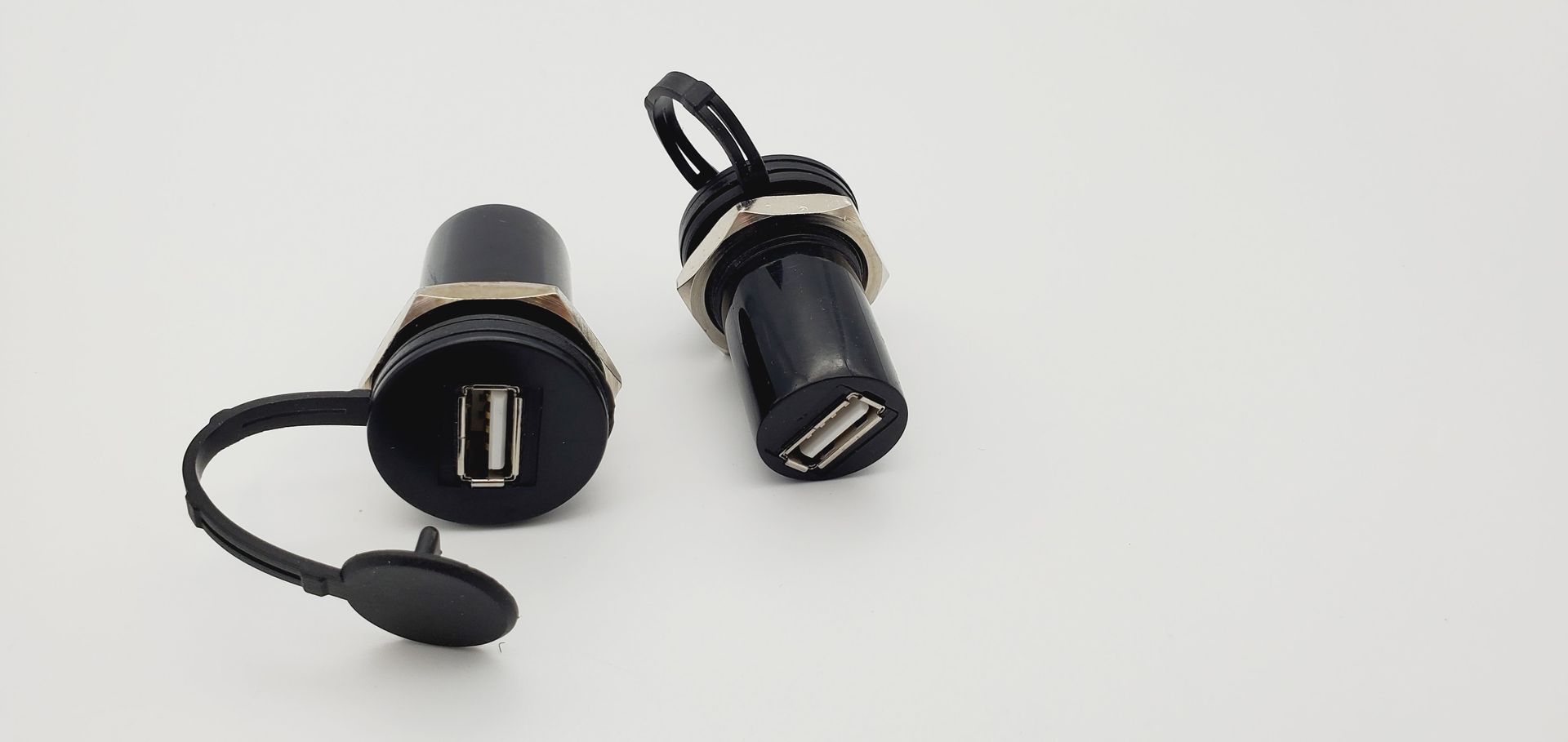 A pair of black usb chargers are sitting next to each other on a white surface.