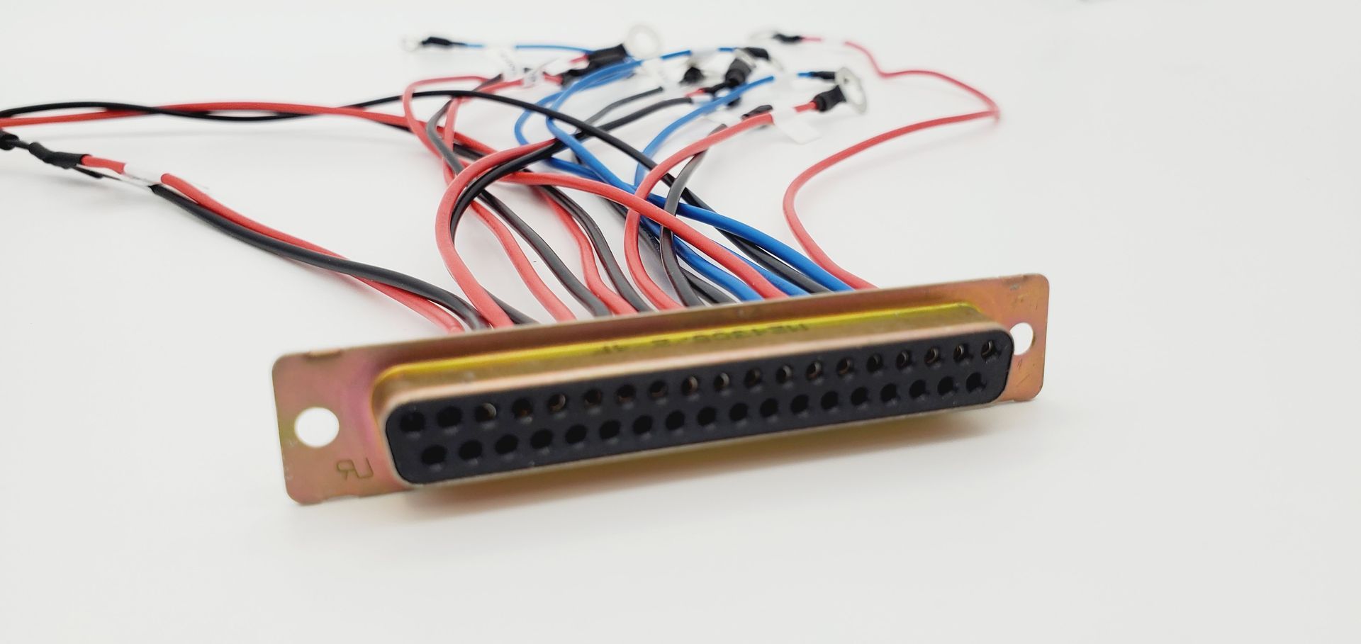 A bunch of wires are connected to a metal connector on a white surface.