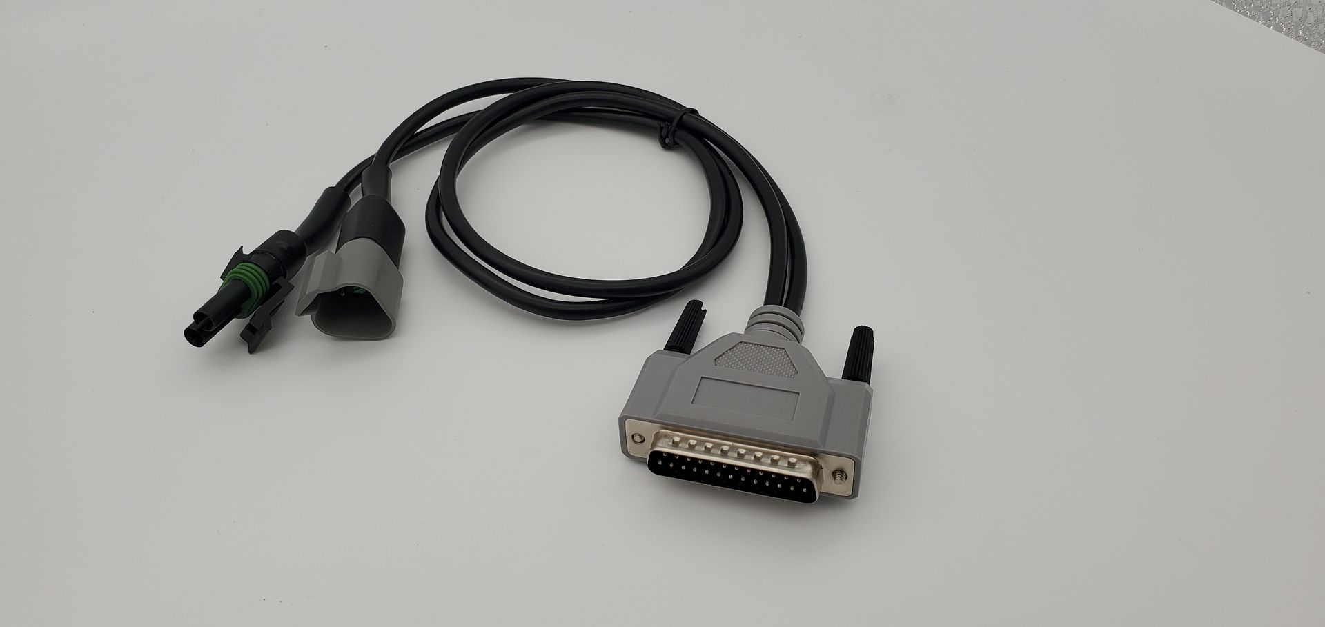A cable with two connectors attached to it is sitting on a white surface.