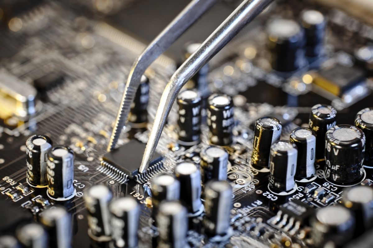A close up of a motherboard with tweezers on it