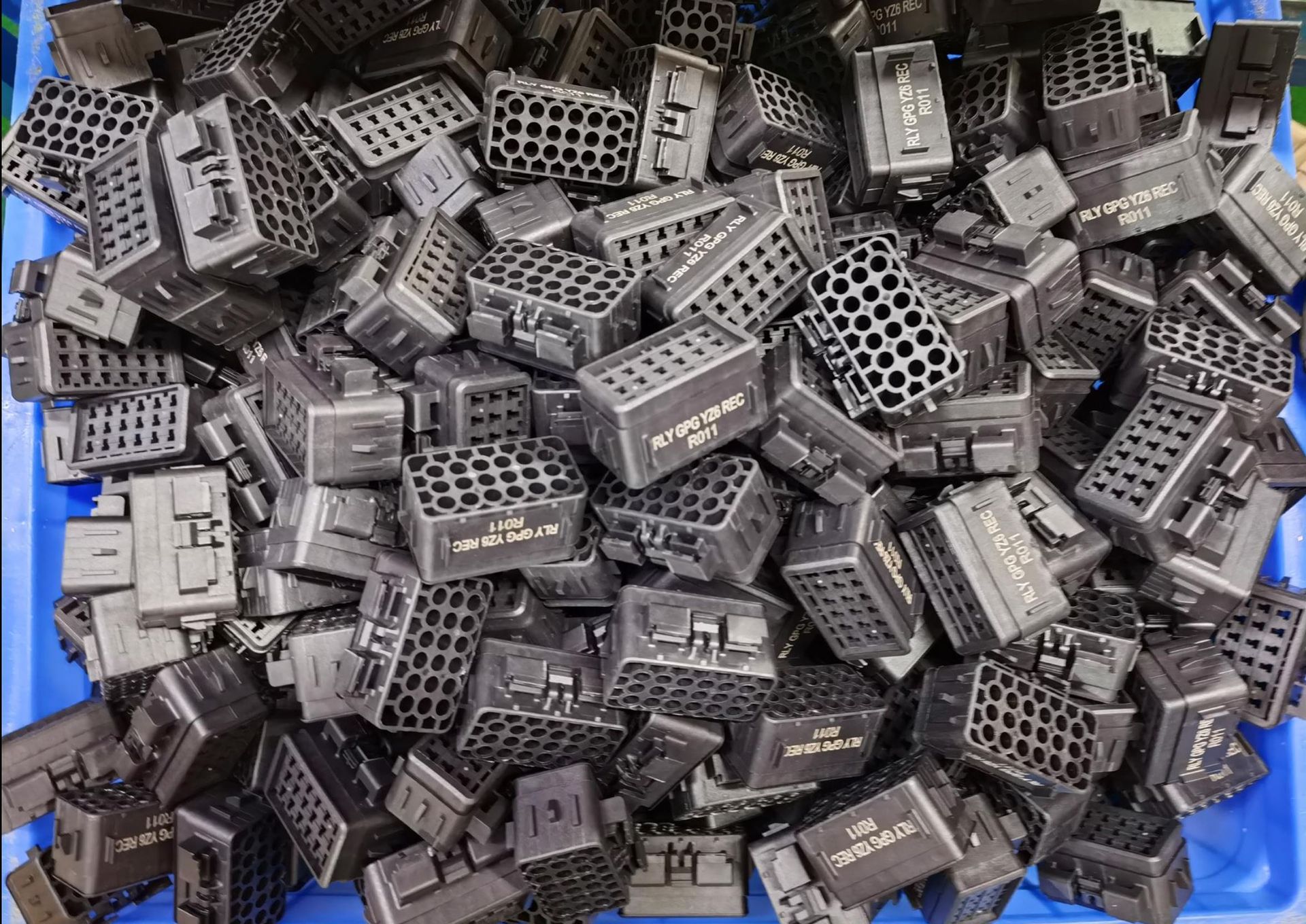 A blue container filled with lots of black plastic blocks
