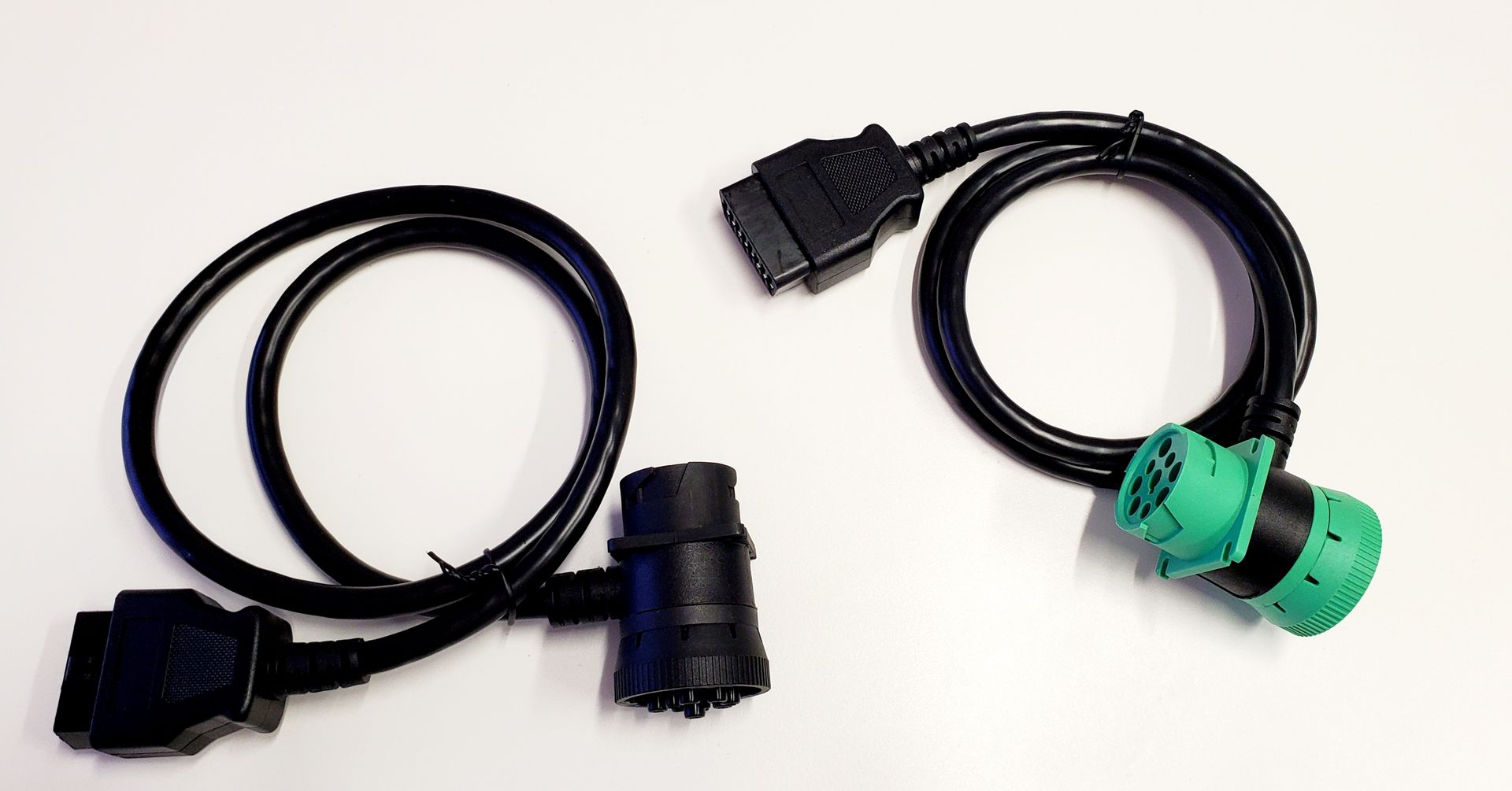 Two black cables with green connectors on a white surface