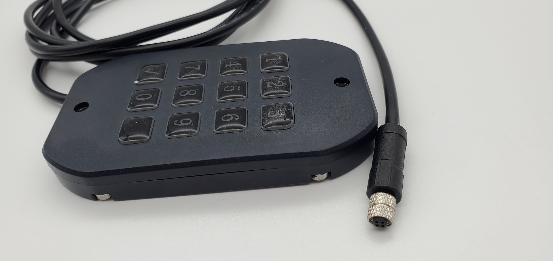 A black device with a cord attached to it is sitting on a white surface.