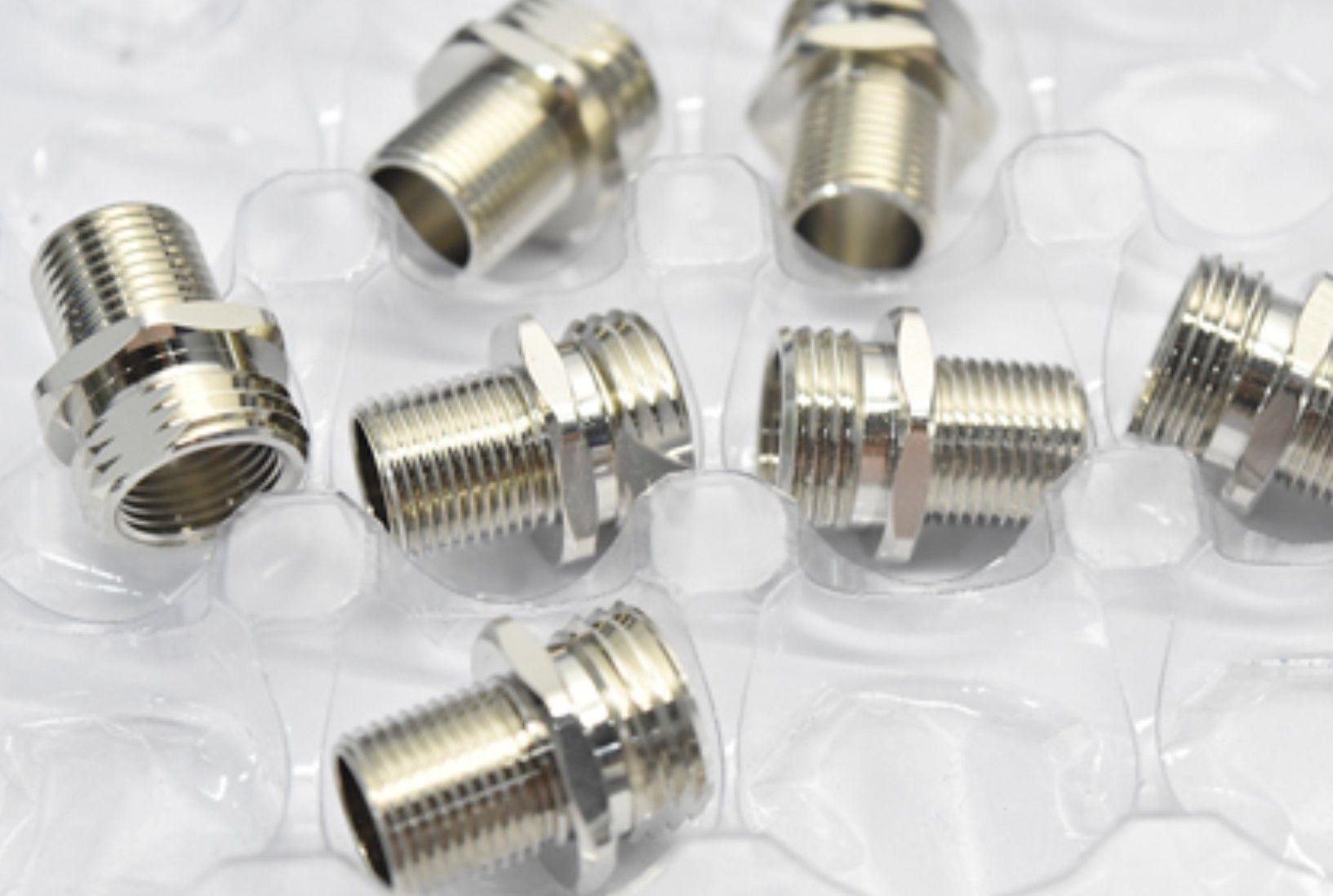 A bunch of metal fittings are sitting on top of each other on a plastic tray.