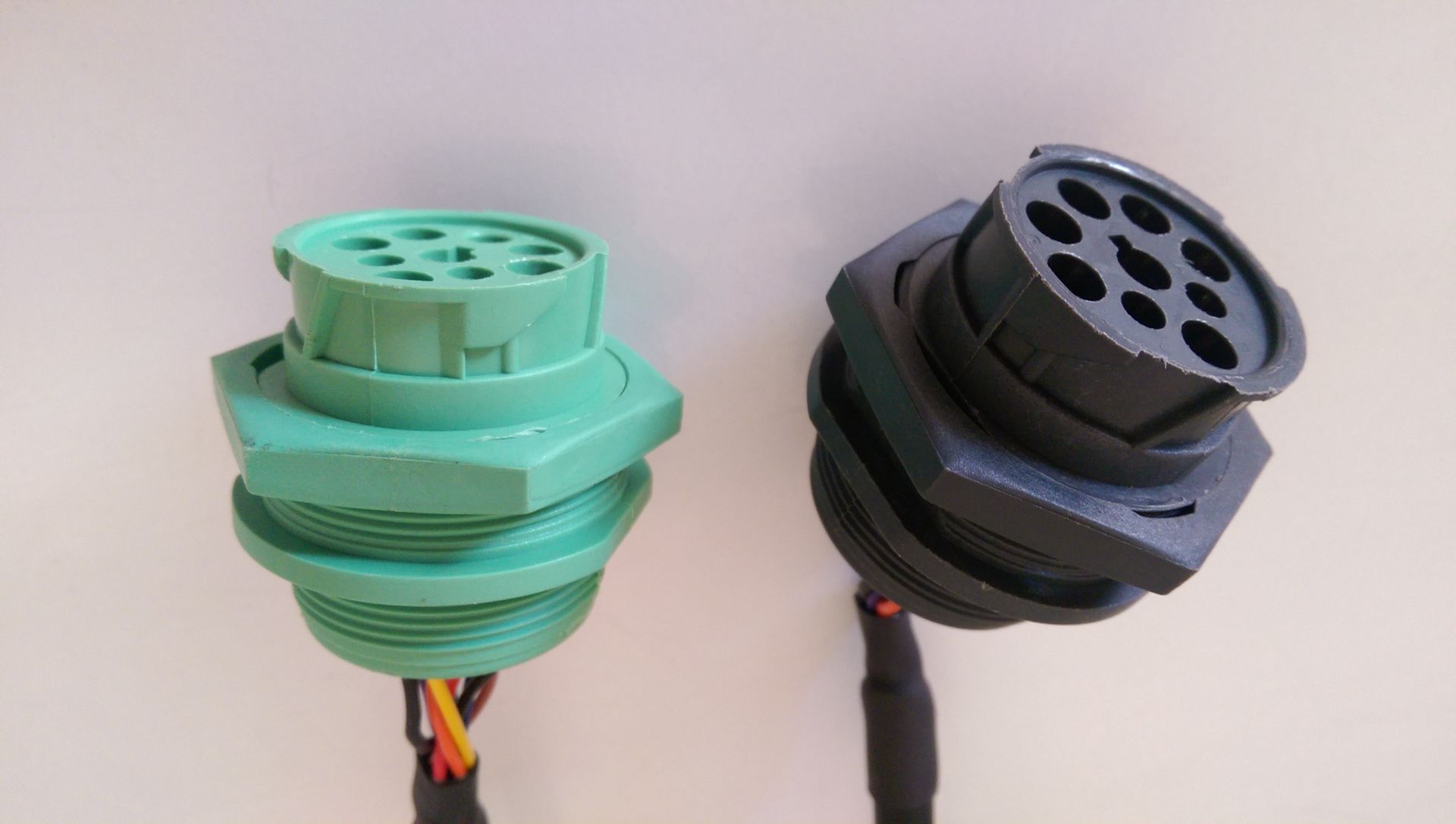 Two electrical connectors are sitting next to each other on a white surface.