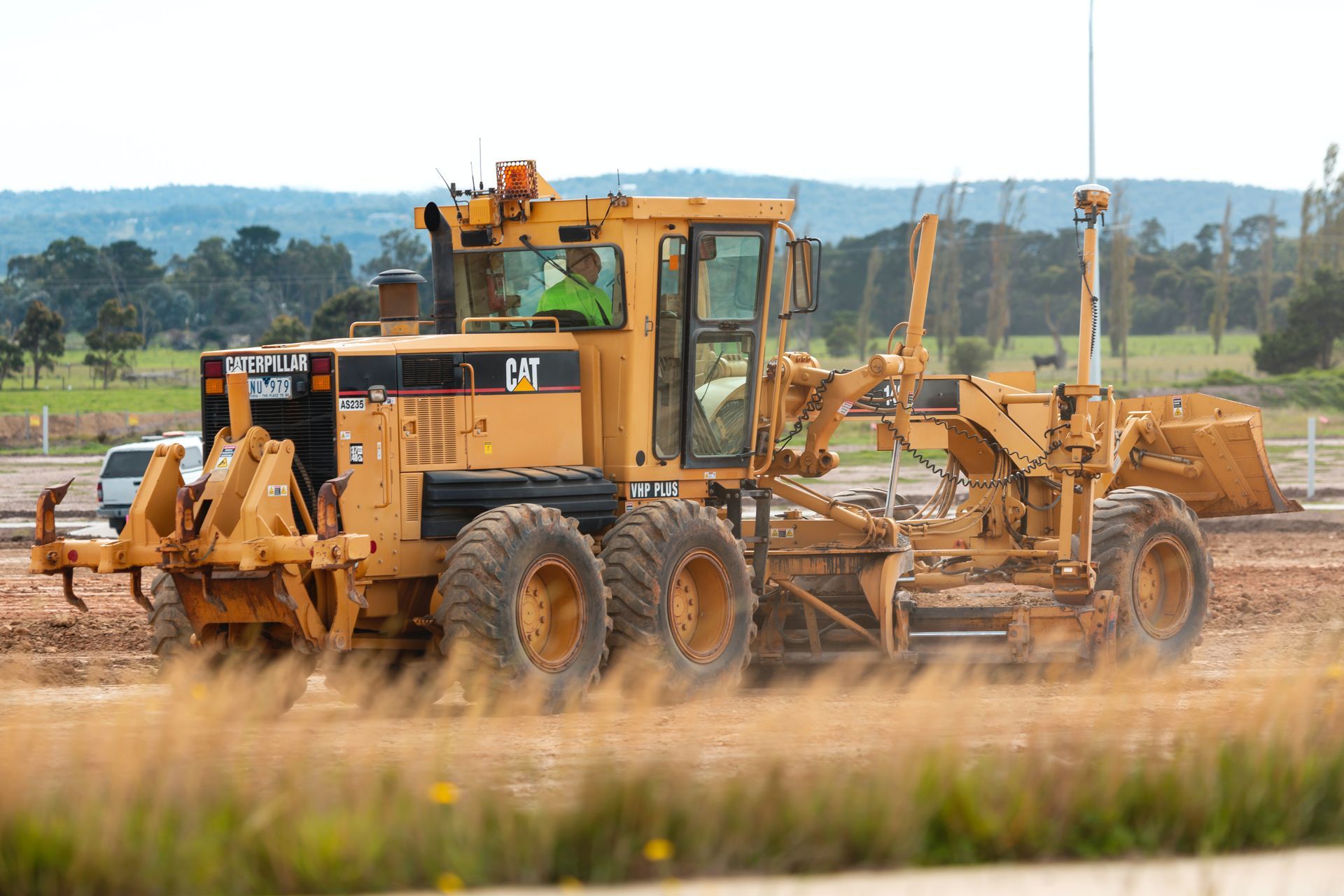 A man is driving a bulldozer on a dirt road.