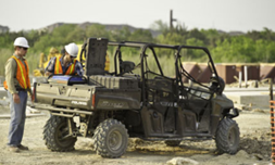 A group of construction workers are standing next to a utility vehicle.