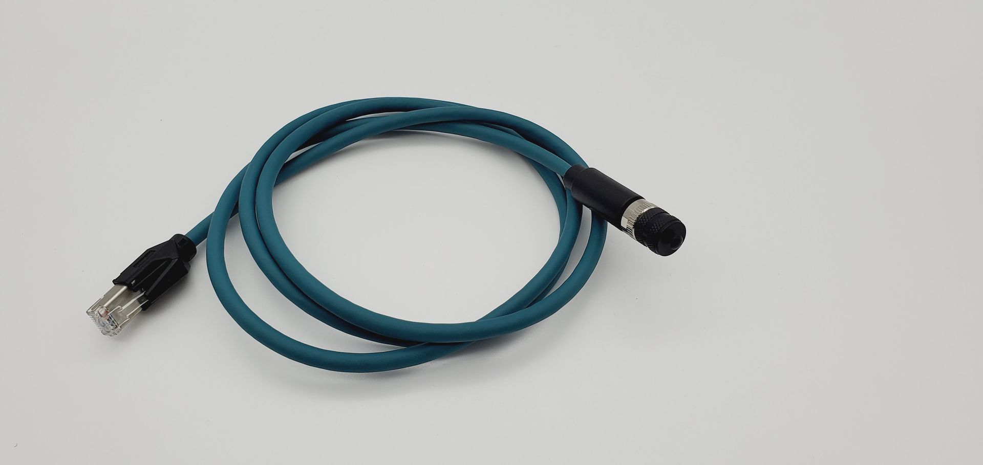 A blue cable with a black plug is sitting on a white surface.