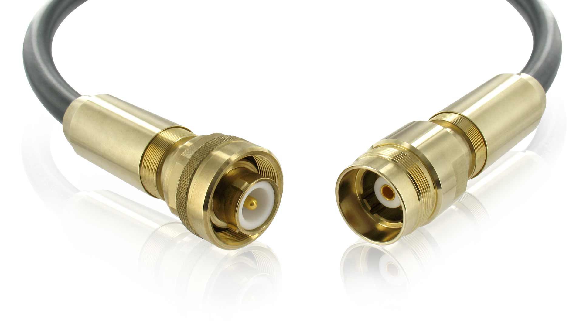A close up of two brass connectors on a cable on a white background.