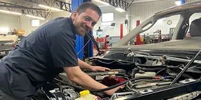 A man is working on the engine of a car in a garage.