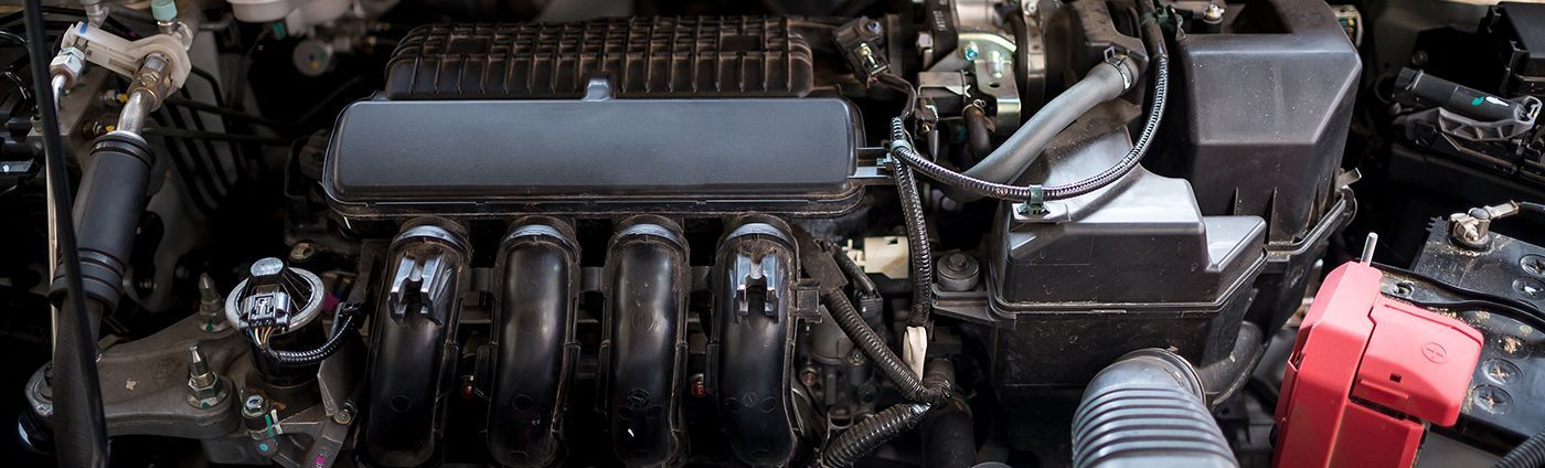 Car engine bay with black intake manifold and red battery on the right