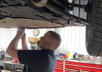 A man is working underneath a car in a garage.