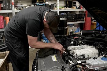 A man is working on the engine of a car in a garage.