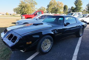 A black pontiac trans am is parked in a parking lot.