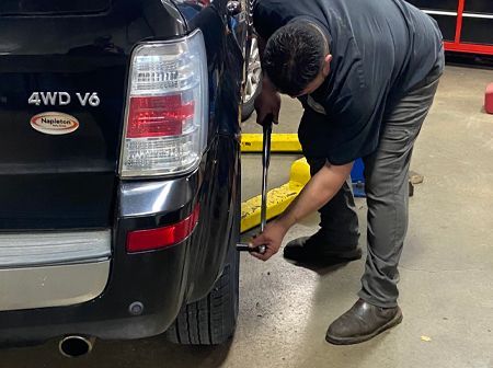 A man is standing next to a tire in a garage.