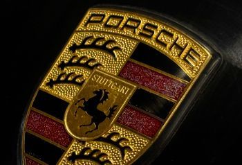 A close up of a porsche logo on a black background