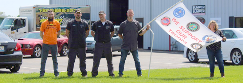 A group of people standing in front of a building holding a flag that says supply only our trucks