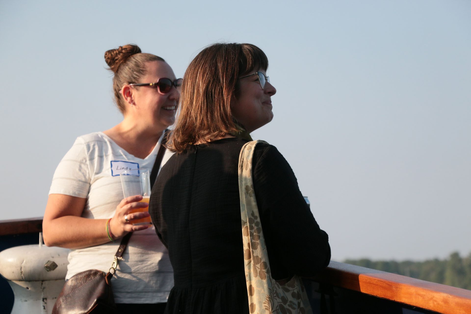 Two people standing at the front of a boat, smiling and looking off to the right.