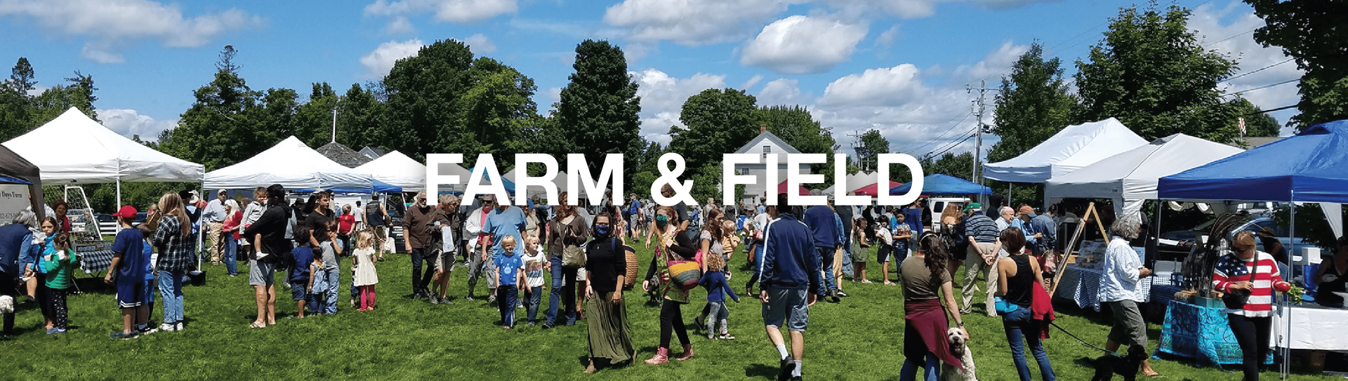 Farm and Field event on a grassy field with crowds of people, white tents, and a blue sky.