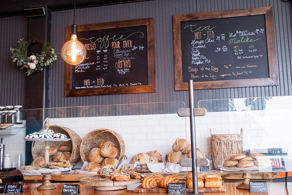 Bakery counter at Boule St Johnsbury with bread, pastries, chalkboards for menu, and a hanging light.