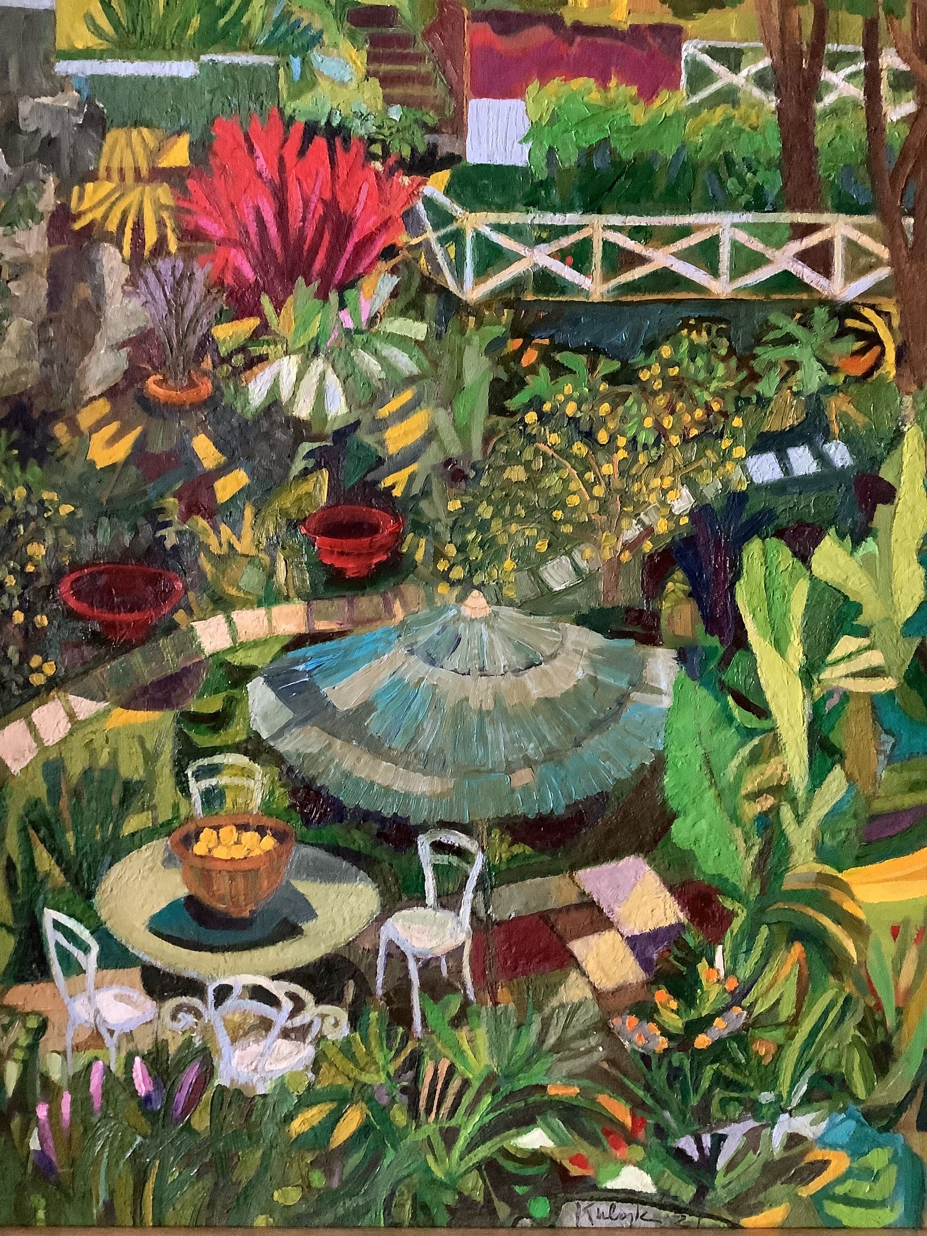 ©Karen Kulyk - Colorful garden scene with chairs, table, and umbrella surrounded by lush foliage and flowers.