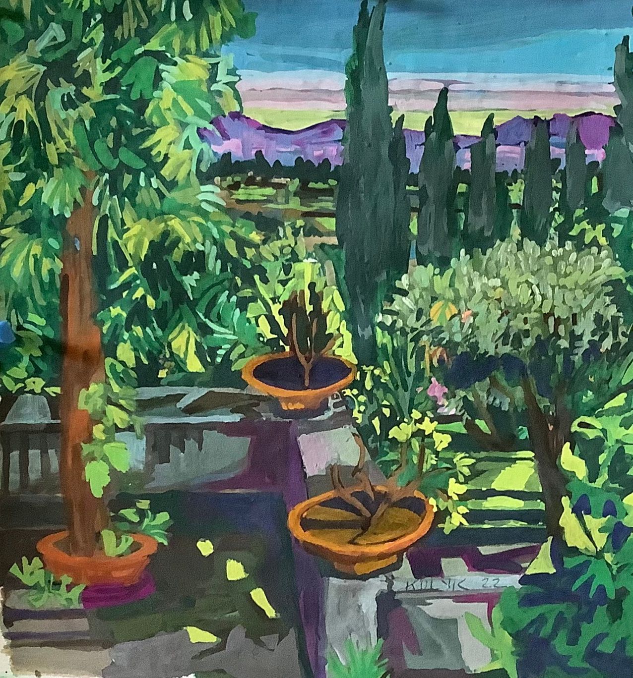 ©Karen Kulyk - A sunlit garden scene with trees, potted plants, and distant purple mountains under a blue sky.