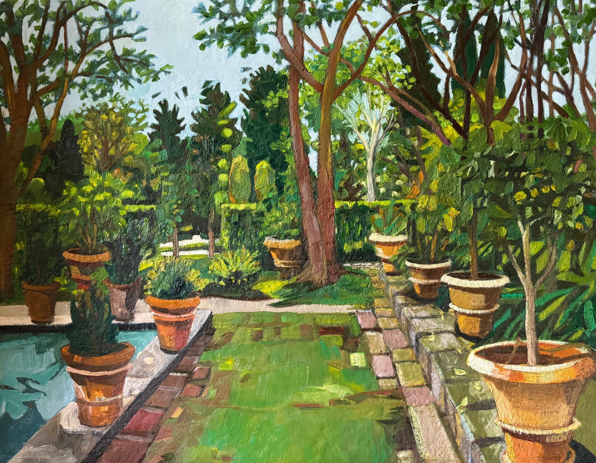 ©Karen Kulyk - A lush garden scene with potted plants, a small pond, and various trees under a bright sky.