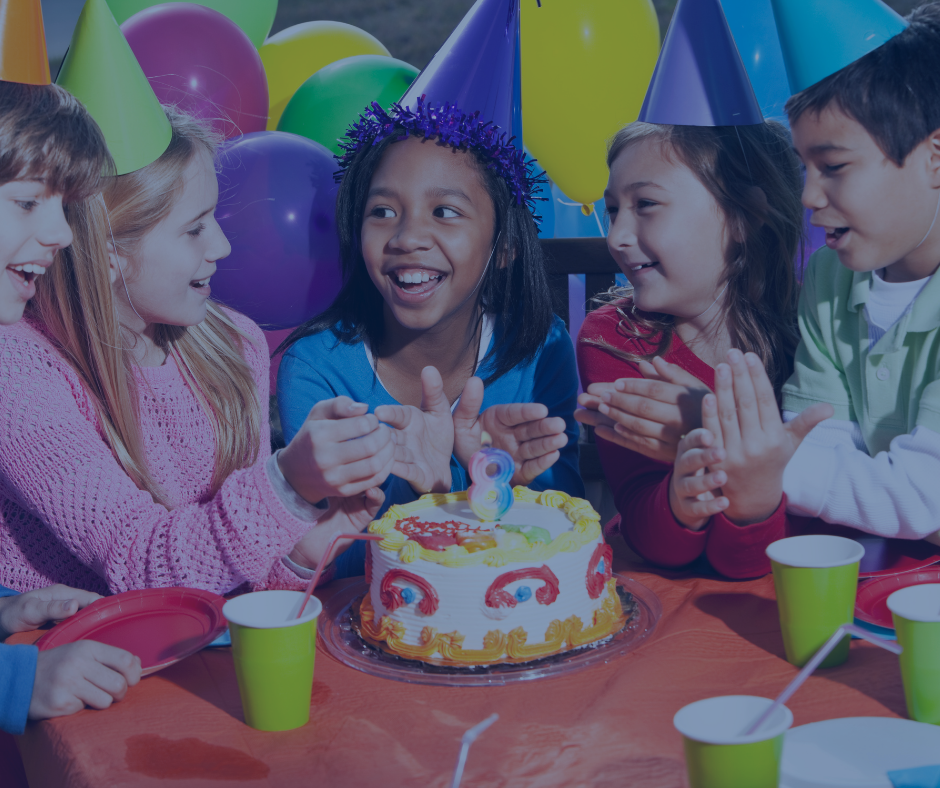 A group of children are sitting around a table with a birthday cake.
