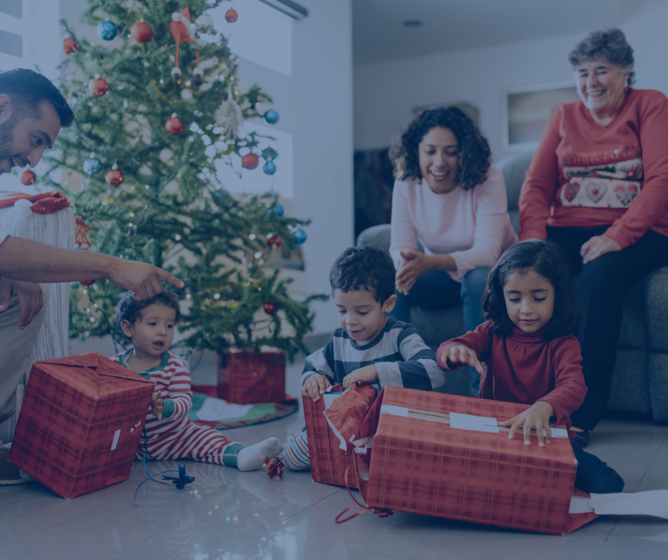 A family is opening christmas presents in front of a christmas tree.