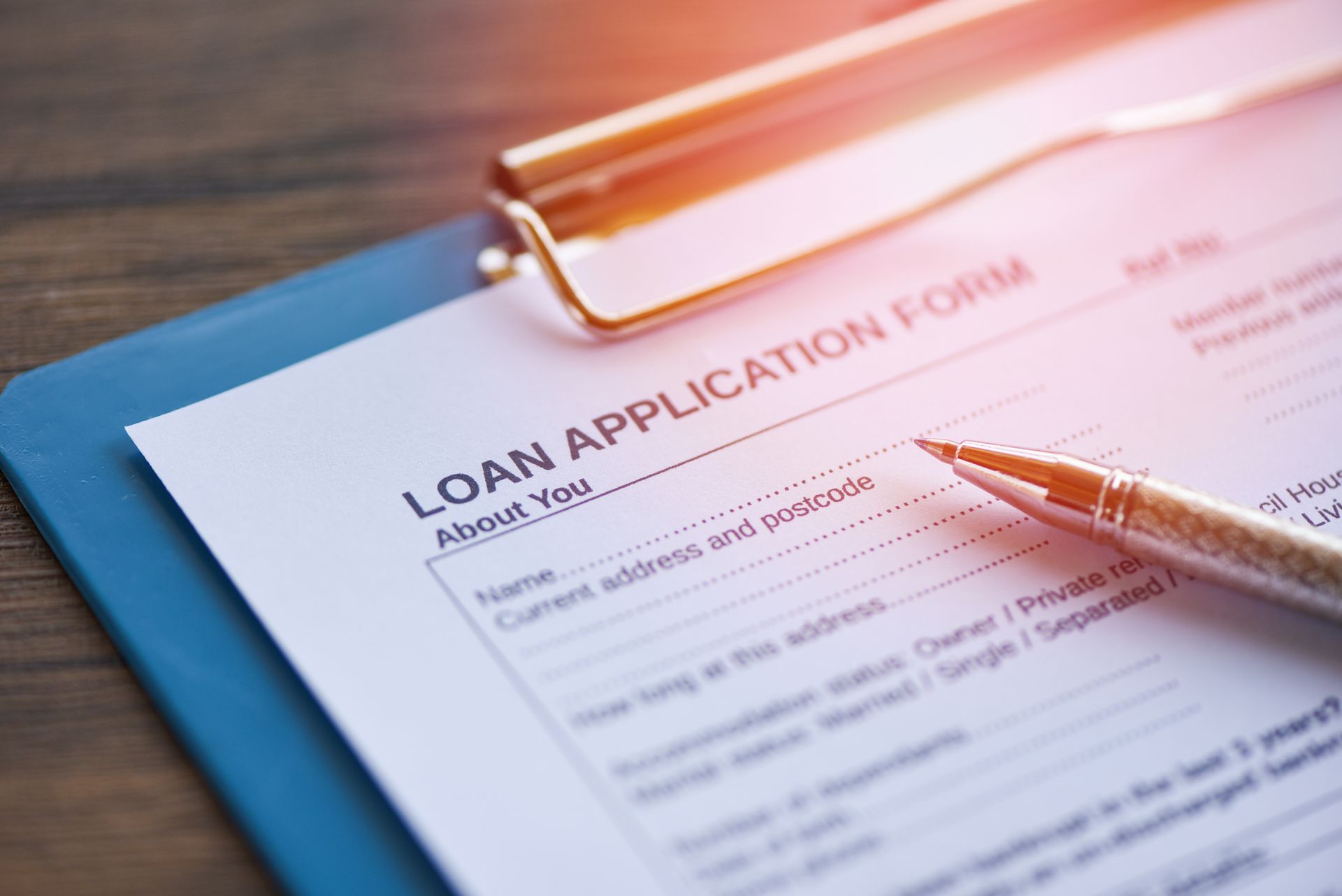 Close-up of a loan application form on a clipboard with a pen resting on top. Close-up of a loan application form on a clipboard with a pen resting on top.