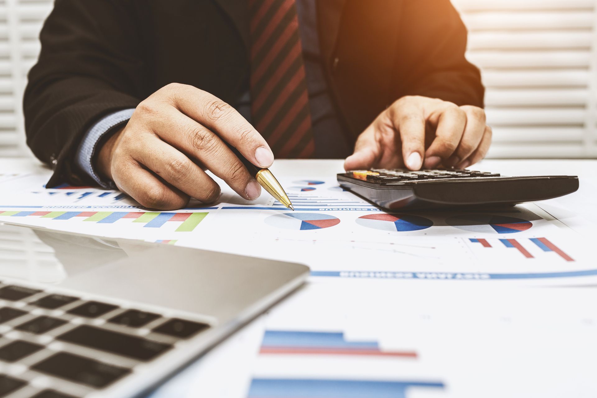 Business professional reviewing financial charts with calculator on desk for financial analysis.